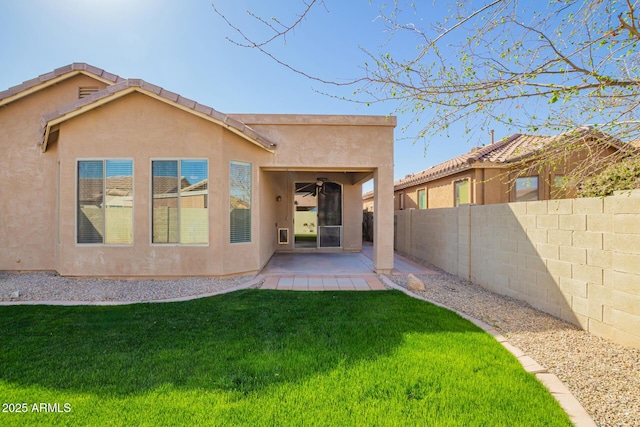 rear view of property featuring a patio area, a fenced backyard, a yard, and stucco siding