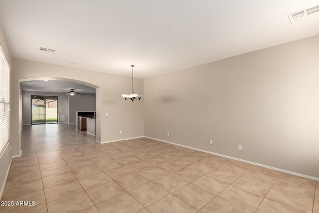 empty room with arched walkways, ceiling fan with notable chandelier, visible vents, and baseboards