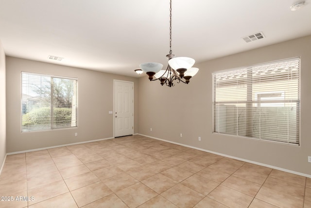 empty room featuring a chandelier, visible vents, and baseboards