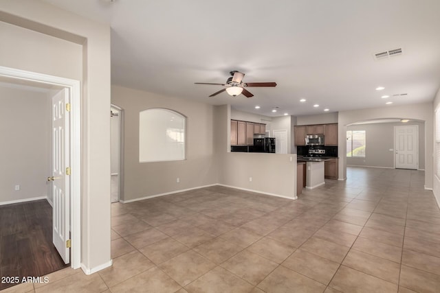 unfurnished living room with visible vents, arched walkways, baseboards, ceiling fan, and recessed lighting