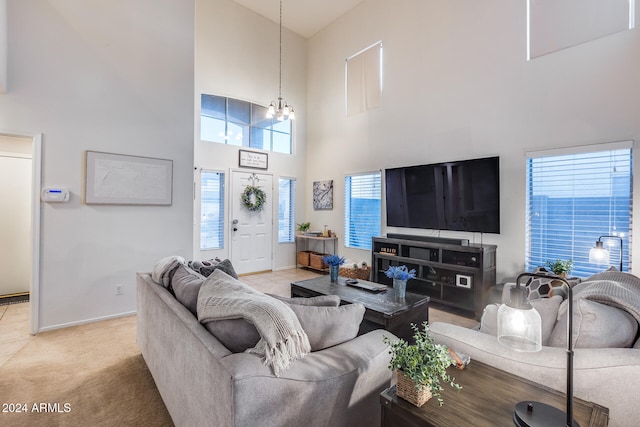 carpeted living room with a towering ceiling, plenty of natural light, and an inviting chandelier