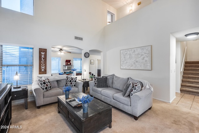 carpeted living room featuring a towering ceiling and ceiling fan