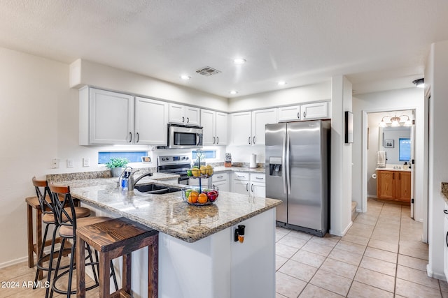 kitchen featuring white cabinets, kitchen peninsula, stainless steel appliances, and sink