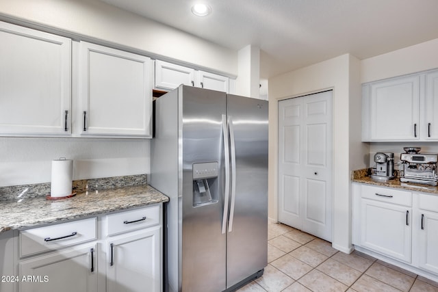 kitchen with white cabinets, stainless steel fridge with ice dispenser, light tile patterned floors, and light stone counters