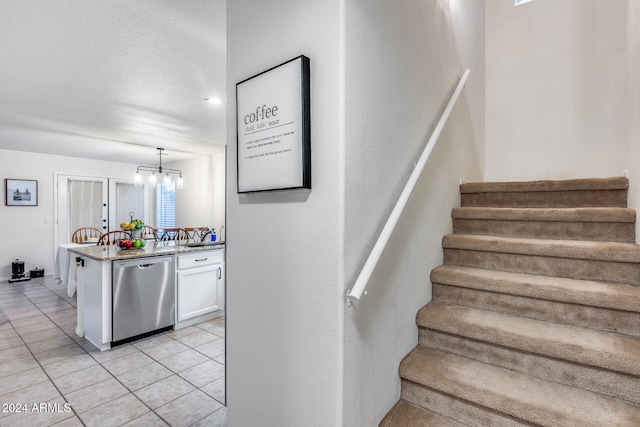 stairway featuring an inviting chandelier, a textured ceiling, and tile patterned flooring