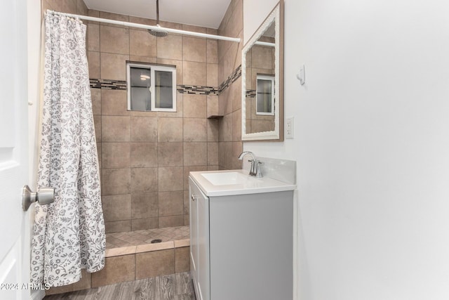 bathroom with a tile shower and vanity