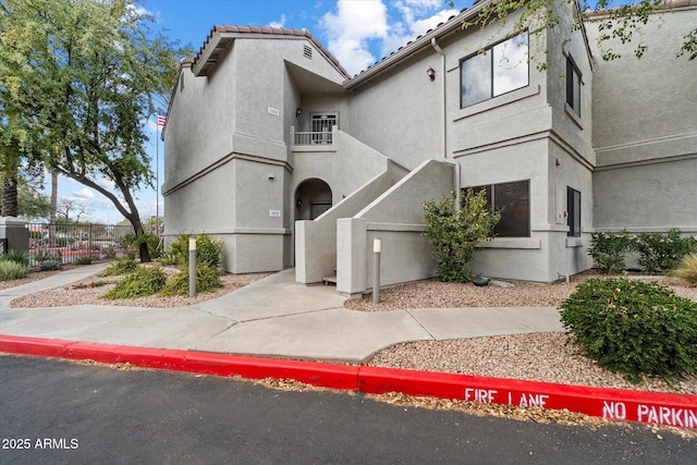 view of front of home with fence, a balcony, and stucco siding