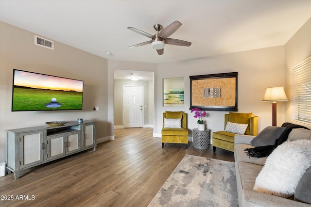 living room featuring a ceiling fan, visible vents, baseboards, and wood finished floors