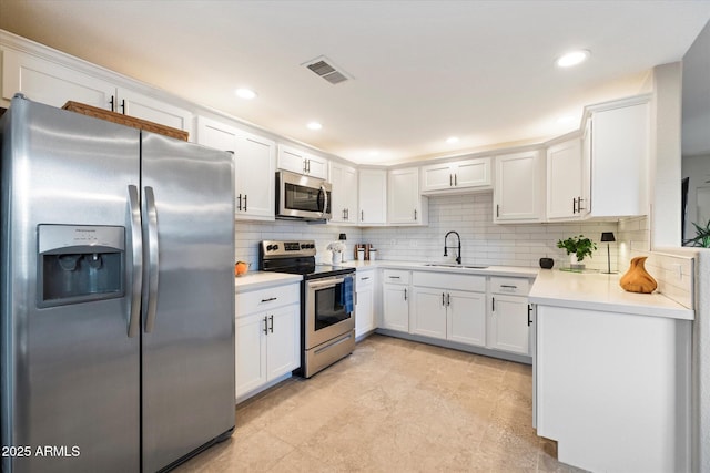 kitchen with a sink, visible vents, white cabinets, appliances with stainless steel finishes, and decorative backsplash