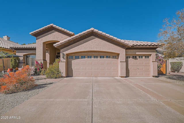 mediterranean / spanish-style home featuring stucco siding, a garage, driveway, and a tile roof