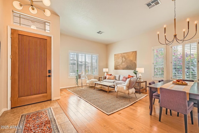 entrance foyer with visible vents, baseboards, a chandelier, and light wood-style flooring