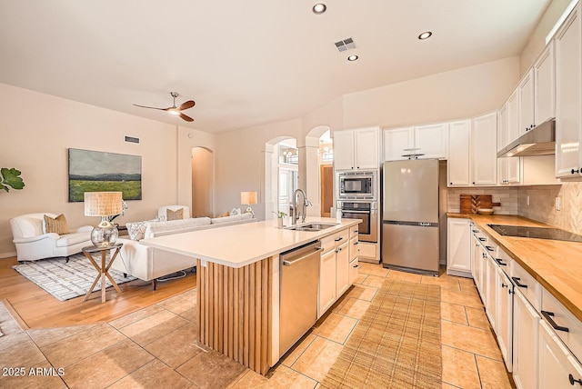 kitchen with visible vents, under cabinet range hood, a sink, arched walkways, and appliances with stainless steel finishes