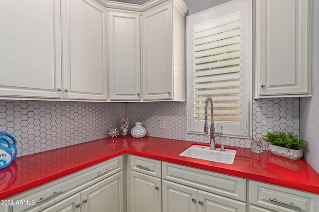 kitchen with white cabinets, sink, and backsplash