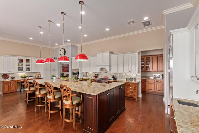 kitchen with a large island, a kitchen bar, dark hardwood / wood-style flooring, and pendant lighting