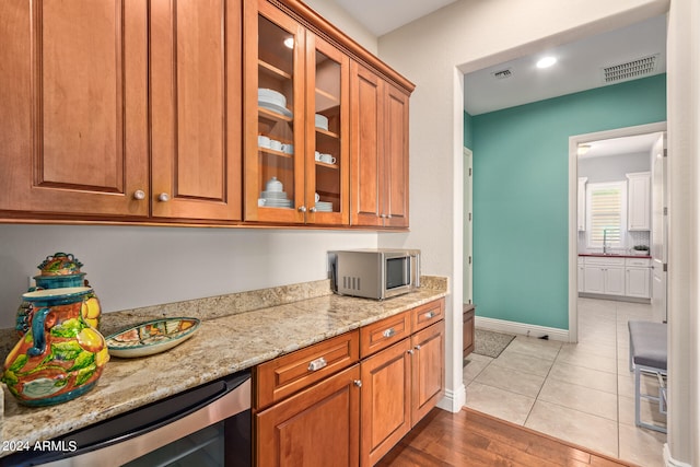 kitchen featuring wine cooler, sink, light stone counters, and light hardwood / wood-style floors