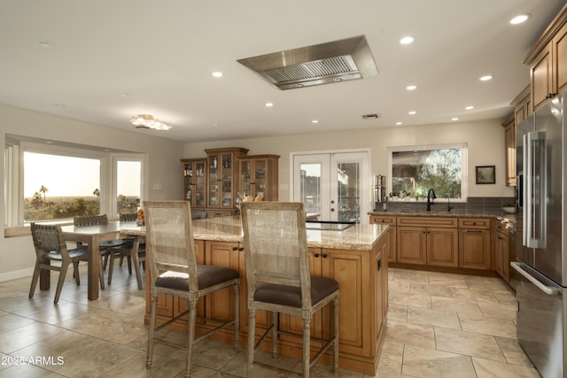 kitchen with french doors, sink, a breakfast bar area, a center island, and high quality fridge