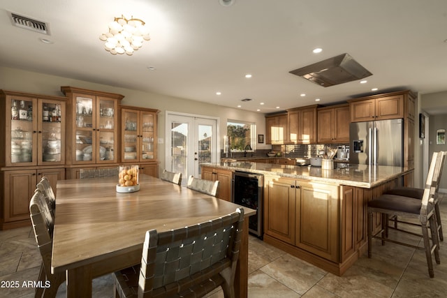 dining space with french doors, beverage cooler, and a chandelier