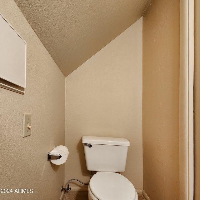 bathroom featuring toilet, a textured ceiling, and lofted ceiling