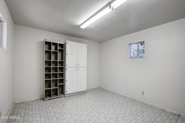 tiled empty room with a textured ceiling