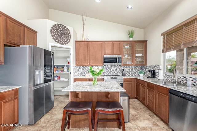 kitchen with appliances with stainless steel finishes, a breakfast bar, sink, a kitchen island, and lofted ceiling