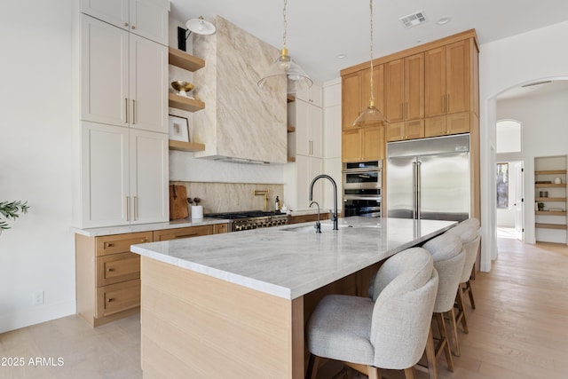 24645 N 117th St, Scottsdale, AZ 85255 - kitchen featuring a sink, arched walkways, stainless steel appliances, open shelves, and decorative backsplash