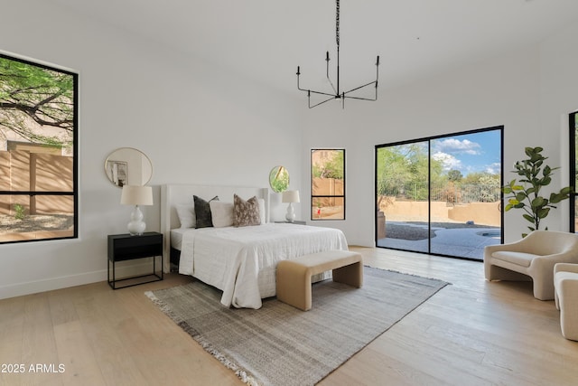 24645 N 117th St, Scottsdale, AZ 85255 - bedroom with access to outside, a chandelier, multiple windows, light wood-style flooring, and a towering ceiling