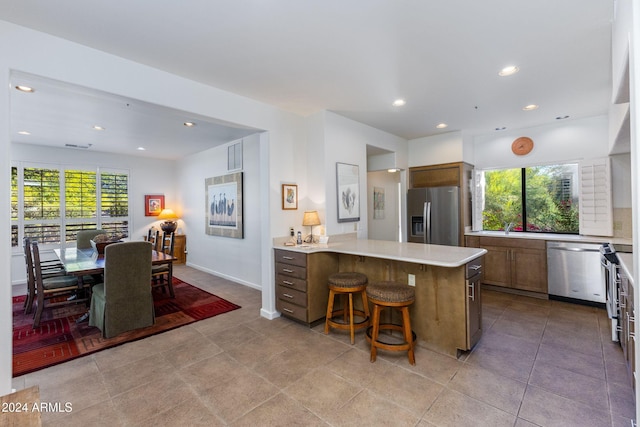 kitchen featuring a kitchen bar, stainless steel appliances, plenty of natural light, and sink