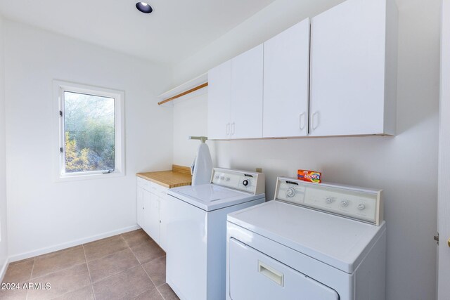 laundry area with washer and dryer, light tile patterned floors, and cabinets