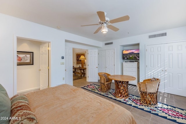 bedroom featuring tile patterned floors, ceiling fan, and two closets