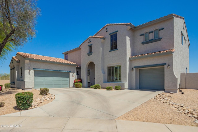 mediterranean / spanish-style home with a tiled roof, concrete driveway, and stucco siding