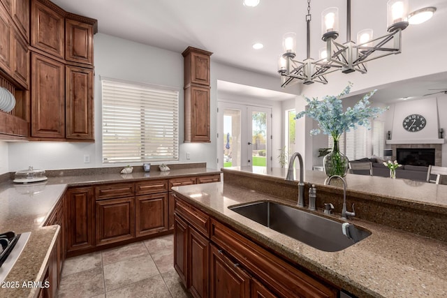 kitchen with a sink, open floor plan, dark stone countertops, pendant lighting, and recessed lighting