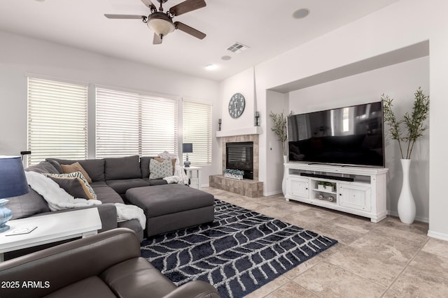 living area with ceiling fan, baseboards, and a tile fireplace