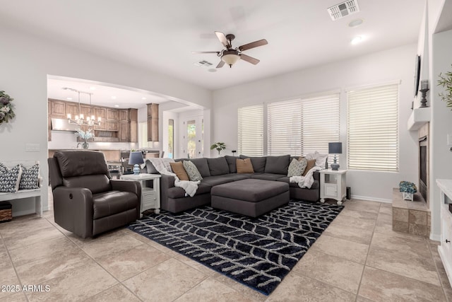 living room with a ceiling fan, light tile patterned floors, a chandelier, arched walkways, and baseboards