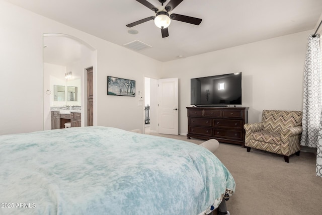 bedroom featuring arched walkways, carpet floors, a ceiling fan, and ensuite bath
