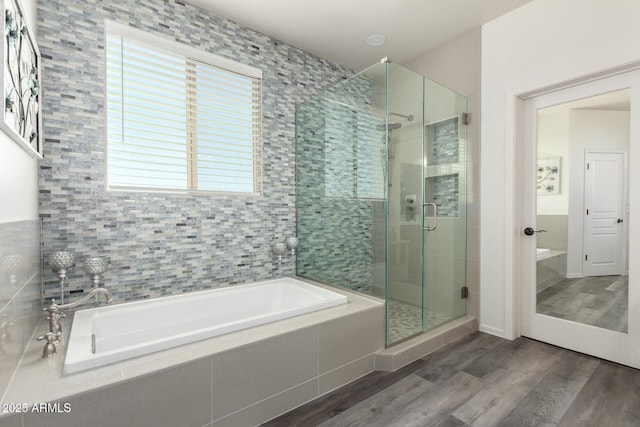 bathroom featuring wood finished floors, a shower stall, and a garden tub
