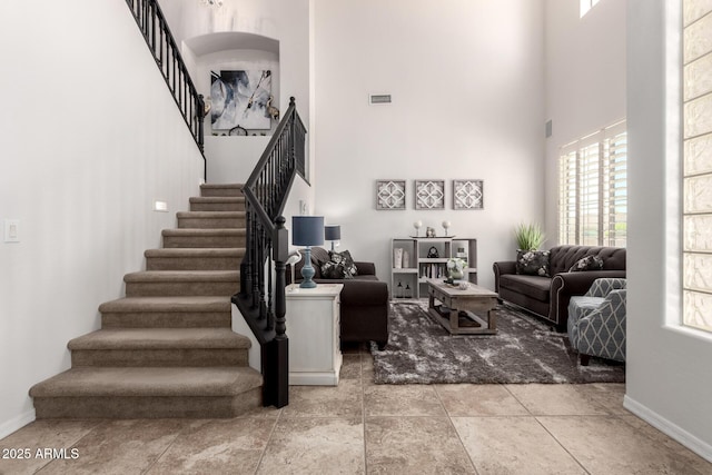 living area with a high ceiling, stairway, and baseboards