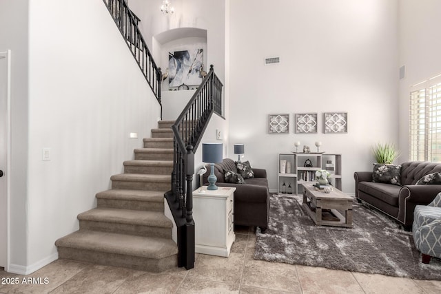 living room featuring a towering ceiling, stairway, and baseboards