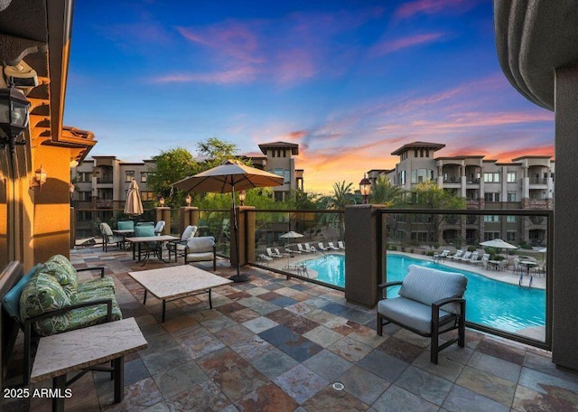 pool at dusk featuring a patio area