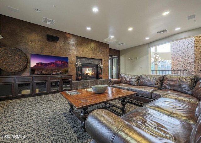 carpeted living room with a notable chandelier and a tiled fireplace