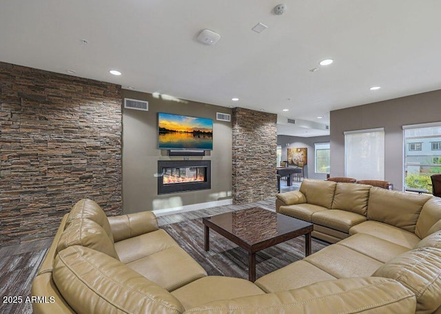 living room with a stone fireplace and dark wood-type flooring