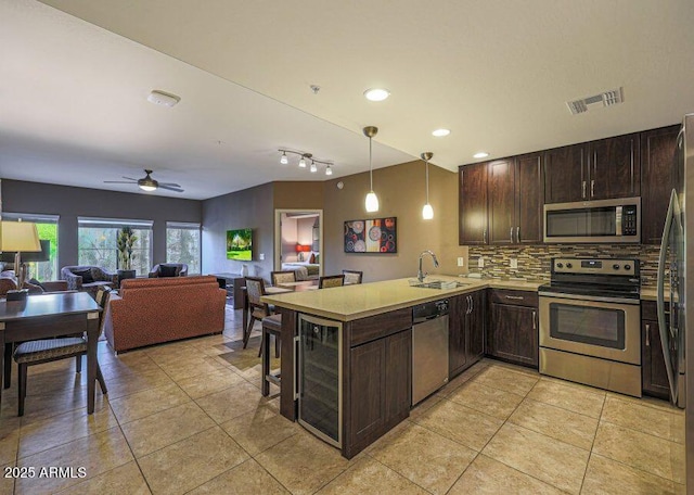 kitchen featuring ceiling fan, stainless steel appliances, kitchen peninsula, pendant lighting, and decorative backsplash