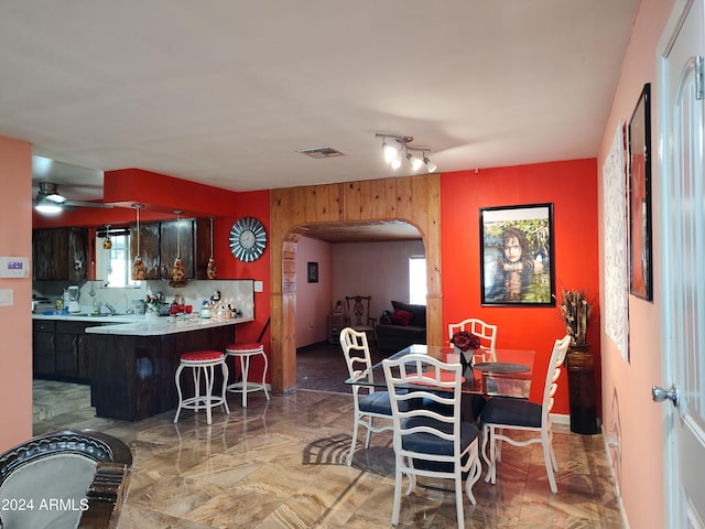 dining area with ceiling fan, a healthy amount of sunlight, and wooden walls