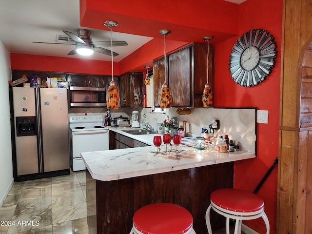 kitchen with sink, a breakfast bar area, dark brown cabinetry, kitchen peninsula, and stainless steel appliances