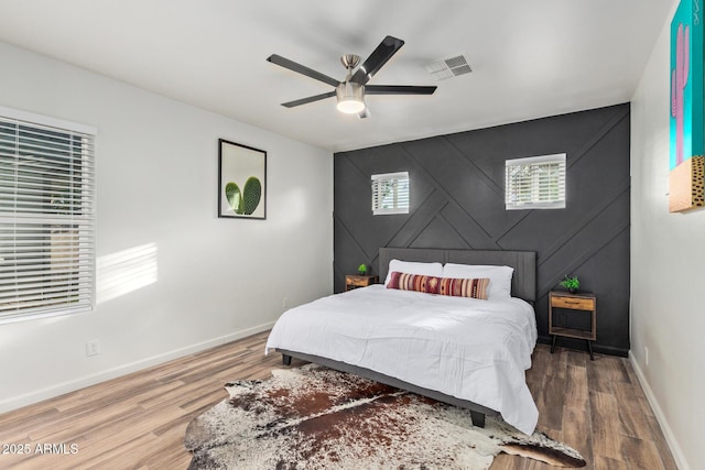 6628 N 2nd Ave, Phoenix, AZ 85013 - bedroom featuring an accent wall, baseboards, wood finished floors, and ceiling fan