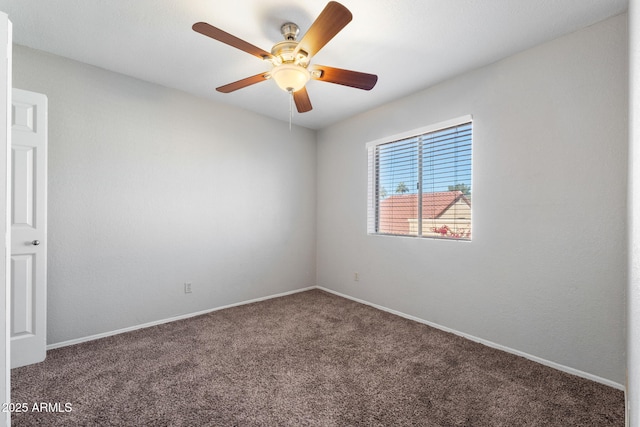 spare room featuring ceiling fan and dark colored carpet