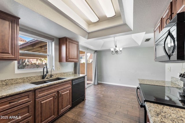 kitchen with sink, light stone counters, dark hardwood / wood-style floors, a tray ceiling, and black appliances