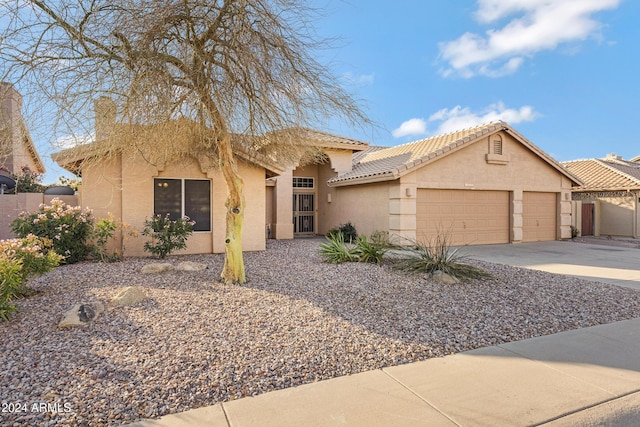 view of front of property featuring a garage, concrete driveway, a tile roof, and stucco siding