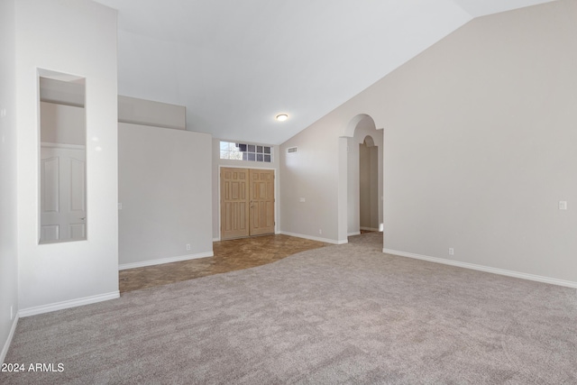 carpeted spare room with high vaulted ceiling, arched walkways, visible vents, and baseboards