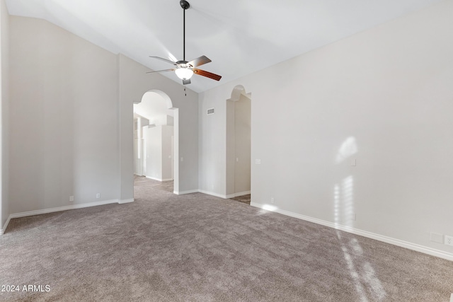 carpeted spare room featuring arched walkways, visible vents, vaulted ceiling, and a ceiling fan