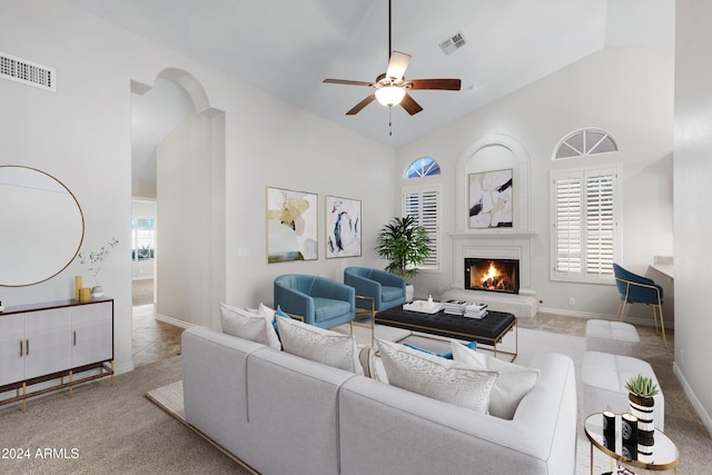 living room with carpet floors, a warm lit fireplace, visible vents, and ceiling fan